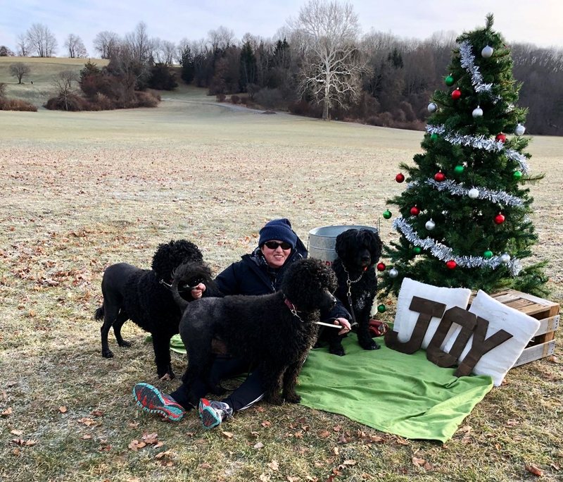 Anat outdoors with three of her dogs beside a decorated tree